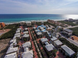 Vista aérea de un complejo turístico costero con varios edificios, una playa y una vista despejada del océano.