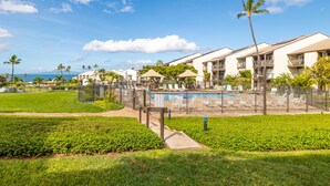 A hotel with a pool area, surrounded by well-maintained lawns and palm trees. - Incredible Ocean View,  Most Desirable Unit in the Complex (Kihei)