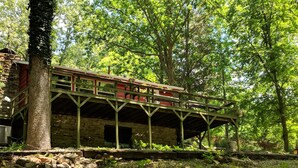 A rustic wooden structure with a balcony, surrounded by lush greenery.