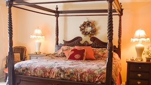 A four-poster bed with a floral bedspread and red pillows, flanked by two bedside tables with lamps. - Gorgeous BROADMOOR English Tudor ~ Delightful Holiday Home, Hot Tub & Gazebo !! (Colorado Springs)