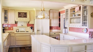 A kitchen with white cabinetry, a central island, a chandelier, and a sign that reads "BON APPETIT". - Gorgeous BROADMOOR English Tudor ~ Delightful Holiday Home, Hot Tub & Gazebo !! (Colorado Springs)