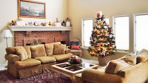 A living room with a fireplace, two sofas, a coffee table, and a Christmas tree. - Gorgeous BROADMOOR English Tudor ~ Delightful Holiday Home, Hot Tub & Gazebo !! (Colorado Springs)