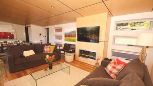 Un salon moderne comprenant un canapé, une table basse, une cheminée et un téléviseur fixé au mur.