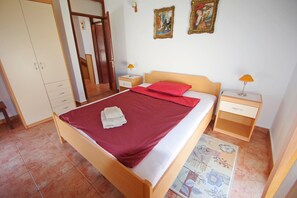 Un dormitorio con cama, armario, dos mesitas de noche y una puerta.