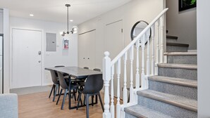 A modern kitchen with a dining area, white staircase, and a ceiling fan. - Newly renovated townhouse - bike right to your door, Private hot tub, BBQ (Silver Star Mountain)