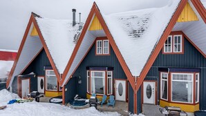 A row of three chalet-style buildings with steeply pitched roofs, each featuring a front porch with outdoor seating. - Newly renovated townhouse - bike right to your door, Private hot tub, BBQ (Silver Star Mountain)