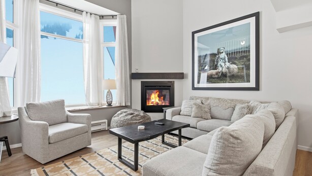 A living room with a fireplace, a sofa, a chair, and a rug. - Newly renovated townhouse - bike right to your door, Private hot tub, BBQ (Silver Star Mountain)