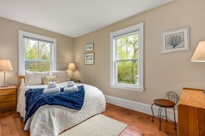 A bedroom with a bed, two bedside lamps, a chair, a desk, and two windows with a view of trees. - Great for groups! Walking distance to Downtown Boothbay Harbor (Boothbay Harbor)