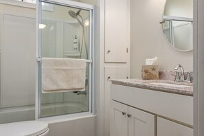 A bathroom with a glass-enclosed shower, a toilet, a sink with a marble countertop, and a mirror. - Great for groups! Walking distance to Downtown Boothbay Harbor (Boothbay Harbor)