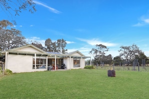 A two-story house with a covered patio area and a fenced yard. - Woongara Cottage: Self-contained cottages on its own private acre (Eagle Point)