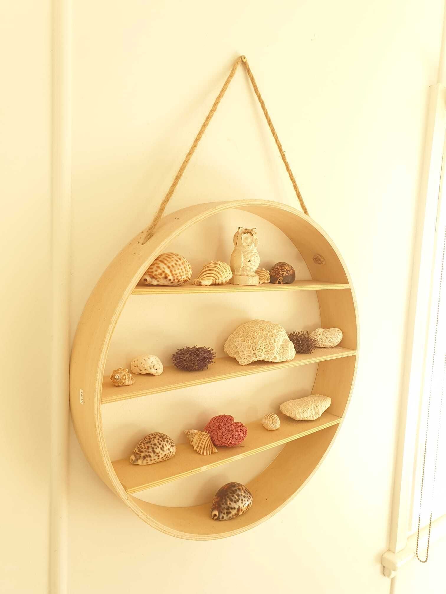 Une étagère circulaire en bois, dotée de plusieurs compartiments, chacun contenant divers objets décoratifs.