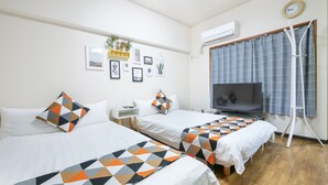Habitación de hotel con dos camas, televisión, escritorio y ventana con cortinas.