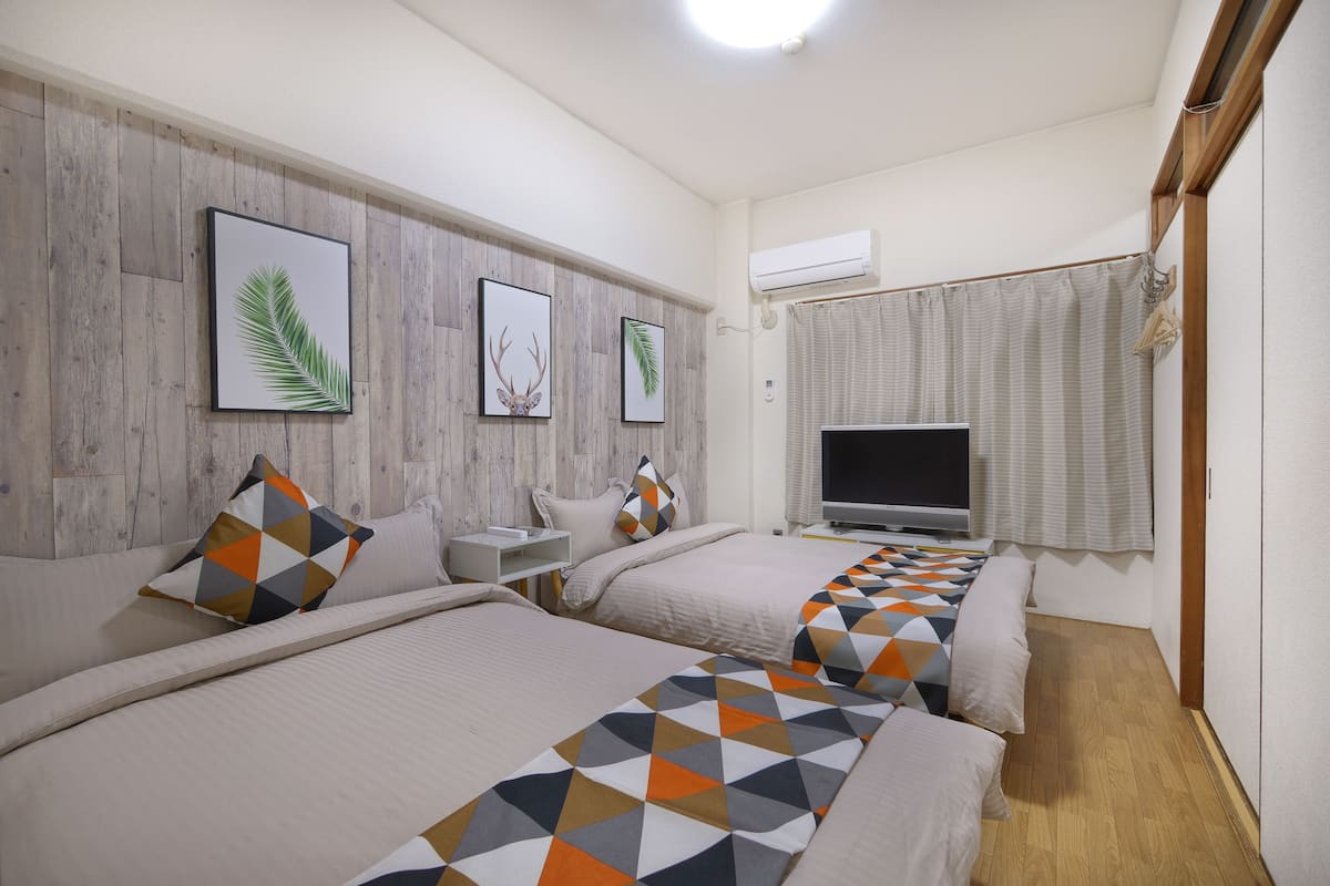 A hotel room with two beds, a flat-screen TV, and a wooden wall panel.