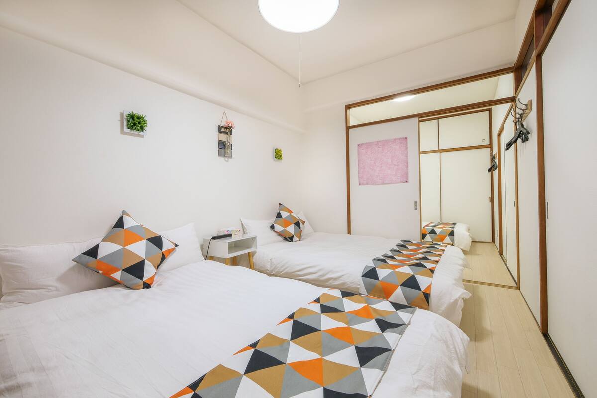 A hotel room with two beds, each with patterned bedding, a small bedside table, and a mirror on the wall.