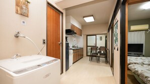 Un espacio habitable compacto con kitchenette, comedor y cama.