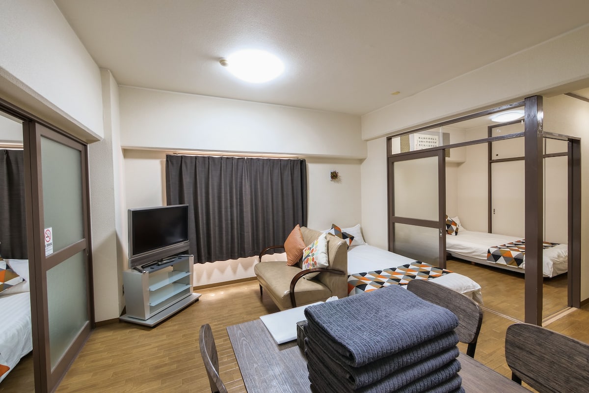 A hotel room with a bed, a desk with a laptop, a TV, and a chair.