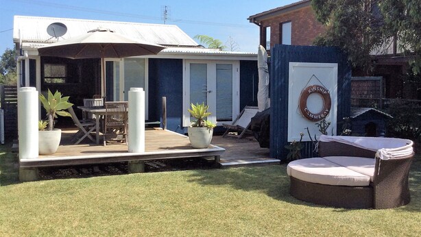 A covered patio with outdoor furniture, a dining table, and potted plants.