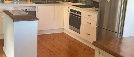 Eine moderne Küche mit Holzschränken, einem Edelstahlkühlschrank und einem Holztisch.