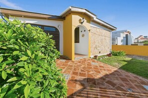 Stunning entrance with arched doorway and beautifully manicured lawn.