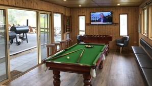A pool table with a green felt surface, a television mounted on the wall, and wooden paneling on the walls and ceiling. - Fawlty Farm in Taylor Bay with 3 FREE experiences (Taylor Bay)