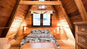 A cozy attic bedroom with a bed, a dresser, and a window with a view of the outdoors. - Fawlty Farm in Taylor Bay with 3 FREE experiences (Taylor Bay)