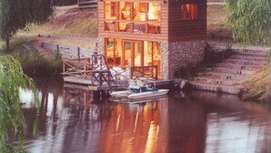 A wooden cabin with a glass front, docked by a calm river. - Fawlty Farm in Taylor Bay with 3 FREE experiences (Taylor Bay)