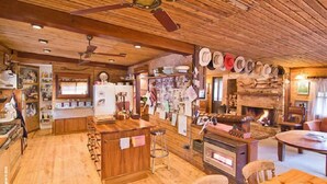 A rustic interior with wooden floors, a kitchen area, a fireplace, and a dining area. - Fawlty Farm in Taylor Bay with 3 FREE experiences (Taylor Bay)