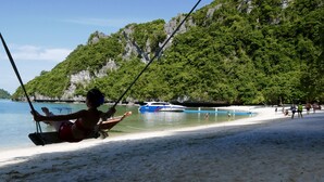 Una spiaggia con un'altalena, acqua cristallina e una barca.