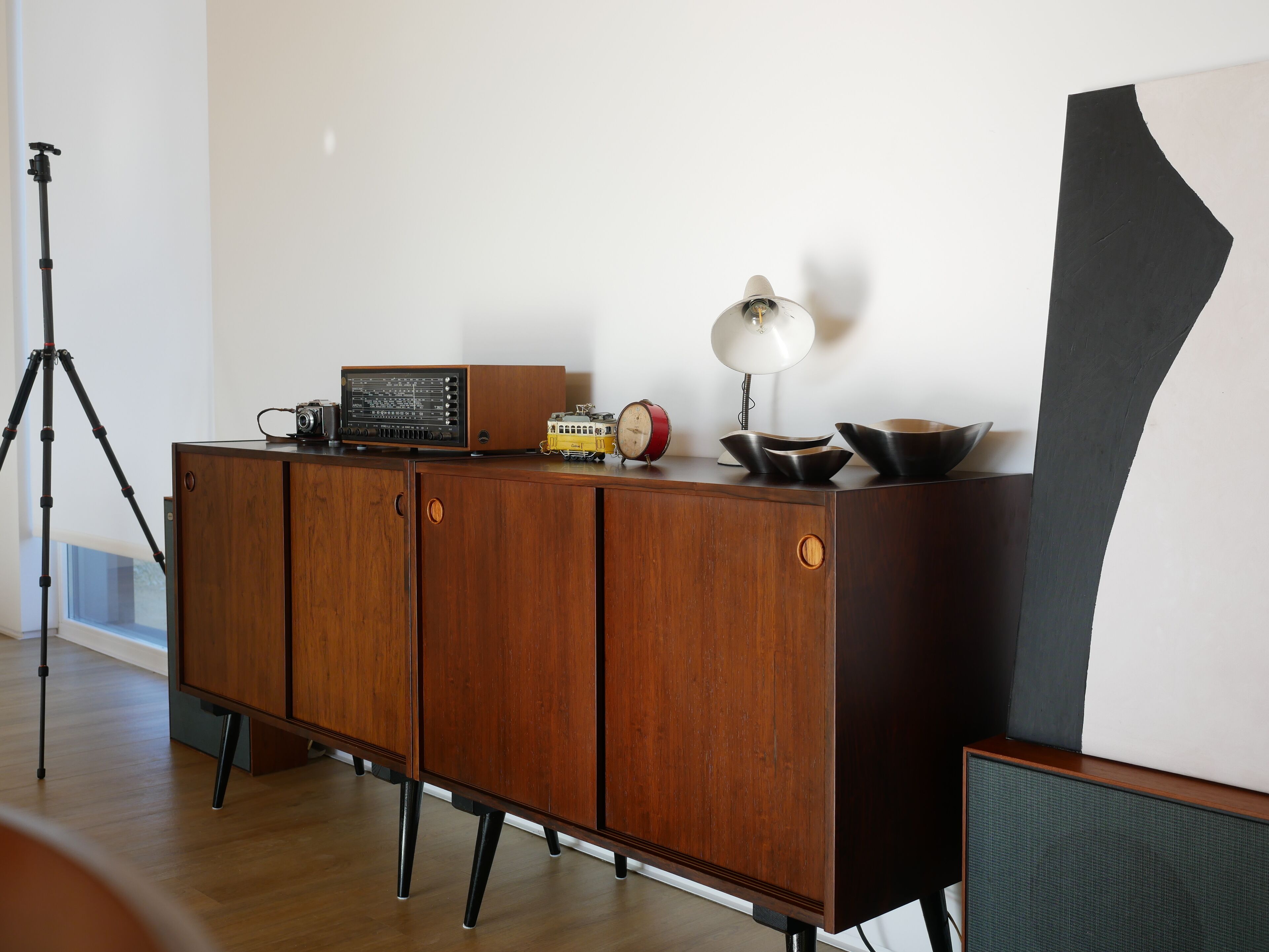 Un mueble de madera con una radio, una lámpara y un reloj encima.