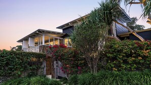 A modern house with a stone facade, a balcony, and lush greenery.