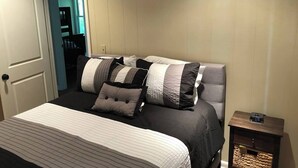 A neatly made bed with striped bedding, a headboard with multiple pillows, and a small bedside table with a clock. - Golf Course Views! Ranch! Fire Pit ! Bring Pets! (West Lafayette)