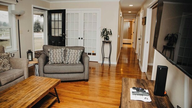 A living room with a grey sofa, wooden coffee table, and a TV on the right wall. - Golf Course Views! Ranch! Fire Pit ! Bring Pets! (West Lafayette)