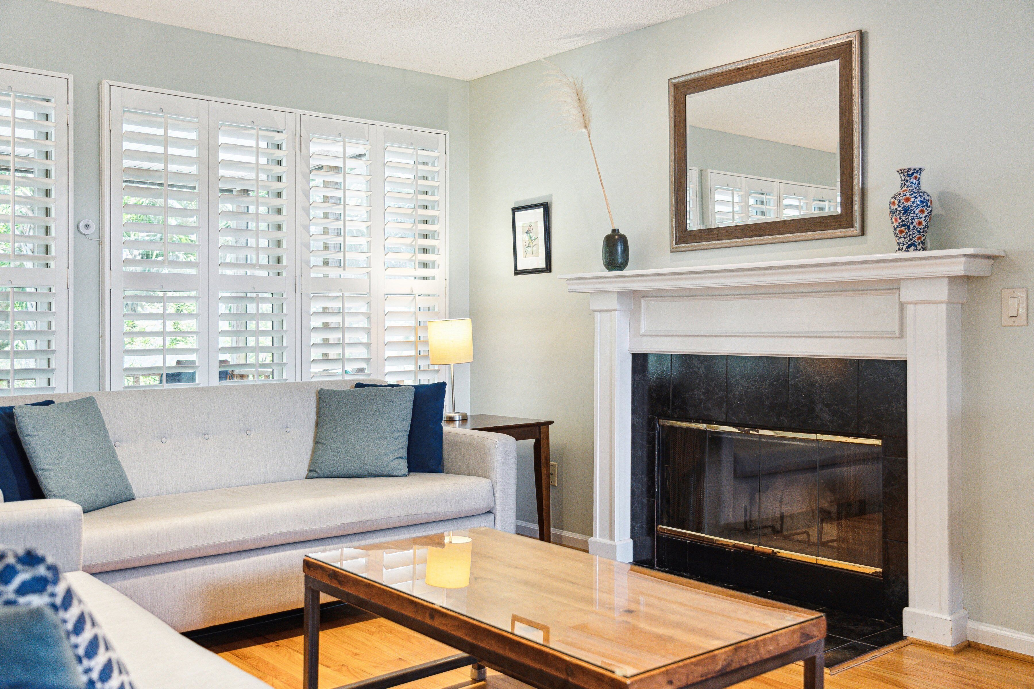 A living room with a sofa, a coffee table, a fireplace, and a large mirror.
