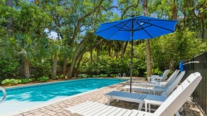 A swimming pool with lounge chairs and a blue umbrella. - Private Oasis with a Large Saltwater Pool Close to Everything - Screened Porch and Deck Open Concept (Folly Beach)