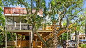 A two-story wooden house with a balcony and a staircase. - Private Oasis with a Large Saltwater Pool Close to Everything - Screened Porch and Deck Open Concept (Folly Beach)