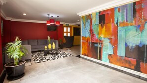 A modern living room with a grey sofa, a black armchair, and a colorful abstract painting on the wall.