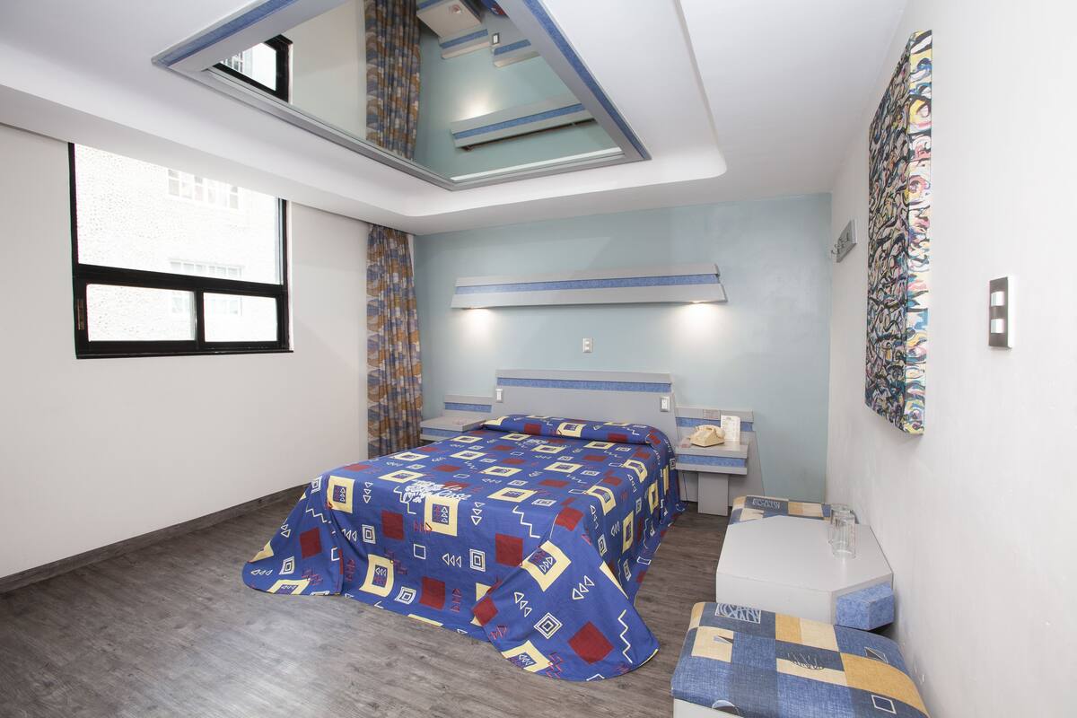 A bedroom with a bed, bedside table, and a window.