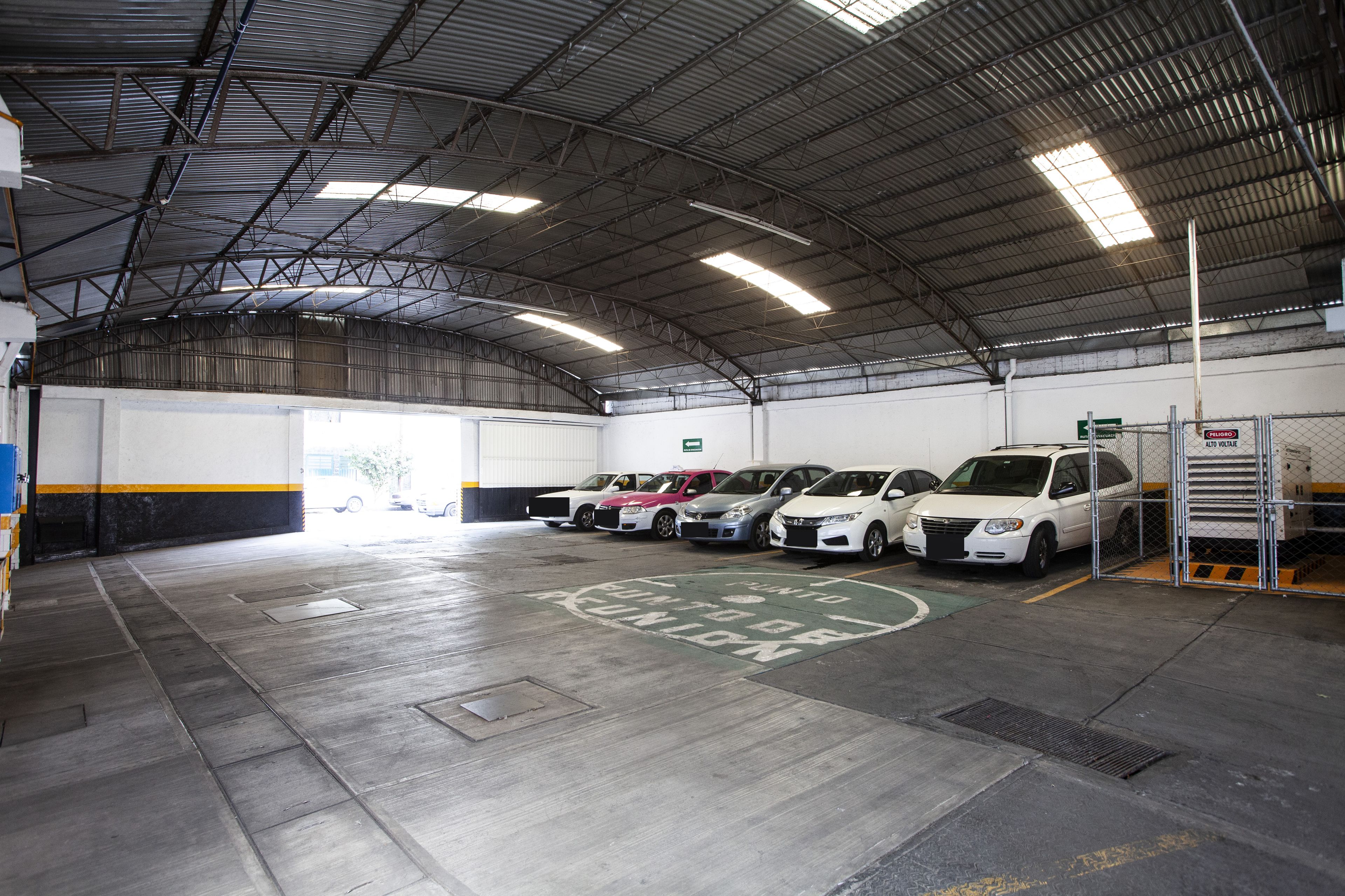 A parking garage with multiple cars parked in designated spaces, a metal roof, and a clean, well-maintained floor.