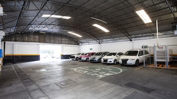A parking garage with multiple cars parked in designated spaces, a metal roof, and a clean, well-maintained floor.