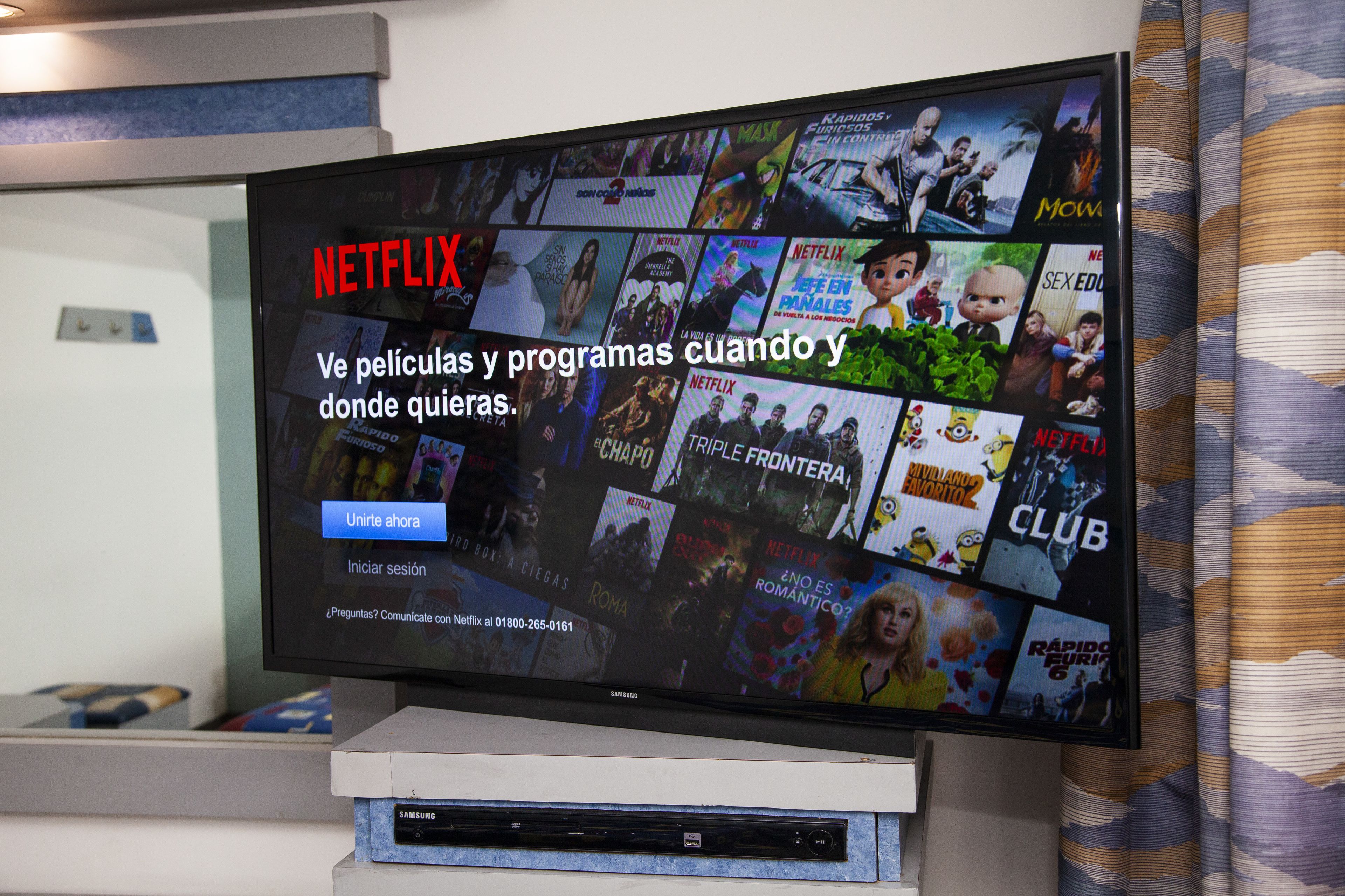 Uma televisão exibindo a interface da Netflix, com diversas miniaturas de filmes e um botão de chamada para ação.
