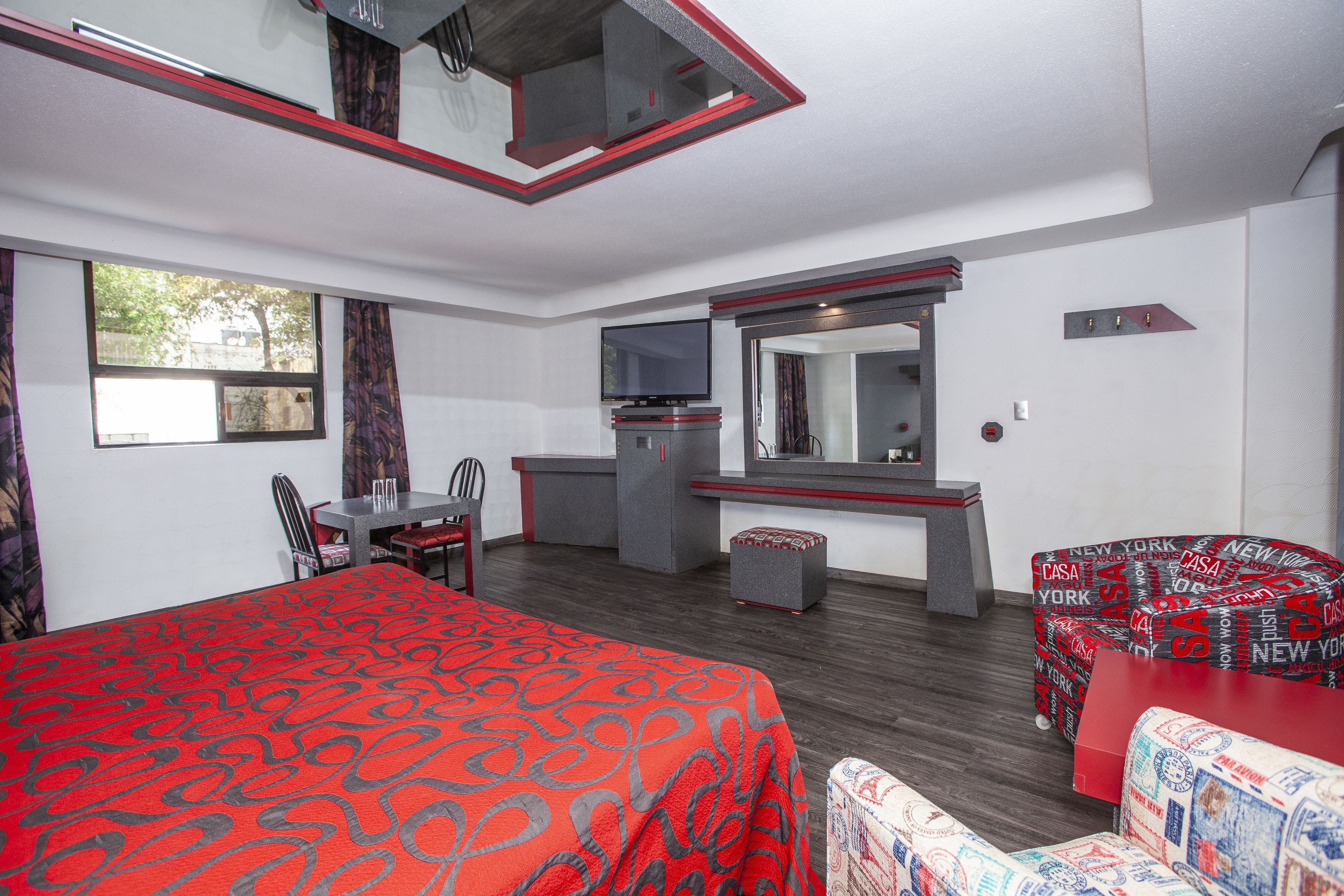 Une chambre d’hôtel avec un lit, un bureau, une chaise, une télévision et une fenêtre.