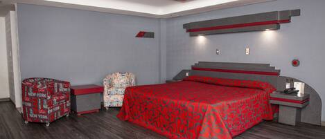A modern bedroom with a large bed, a desk, and a chair.
