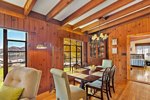 Enjoy meals in this dining area with a large table and comfortable chairs, surrounded by large windows offering a view of the outdoors.