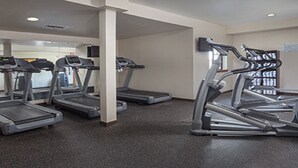 A gym with treadmills and stationary bikes, carpeted floor, and white walls.