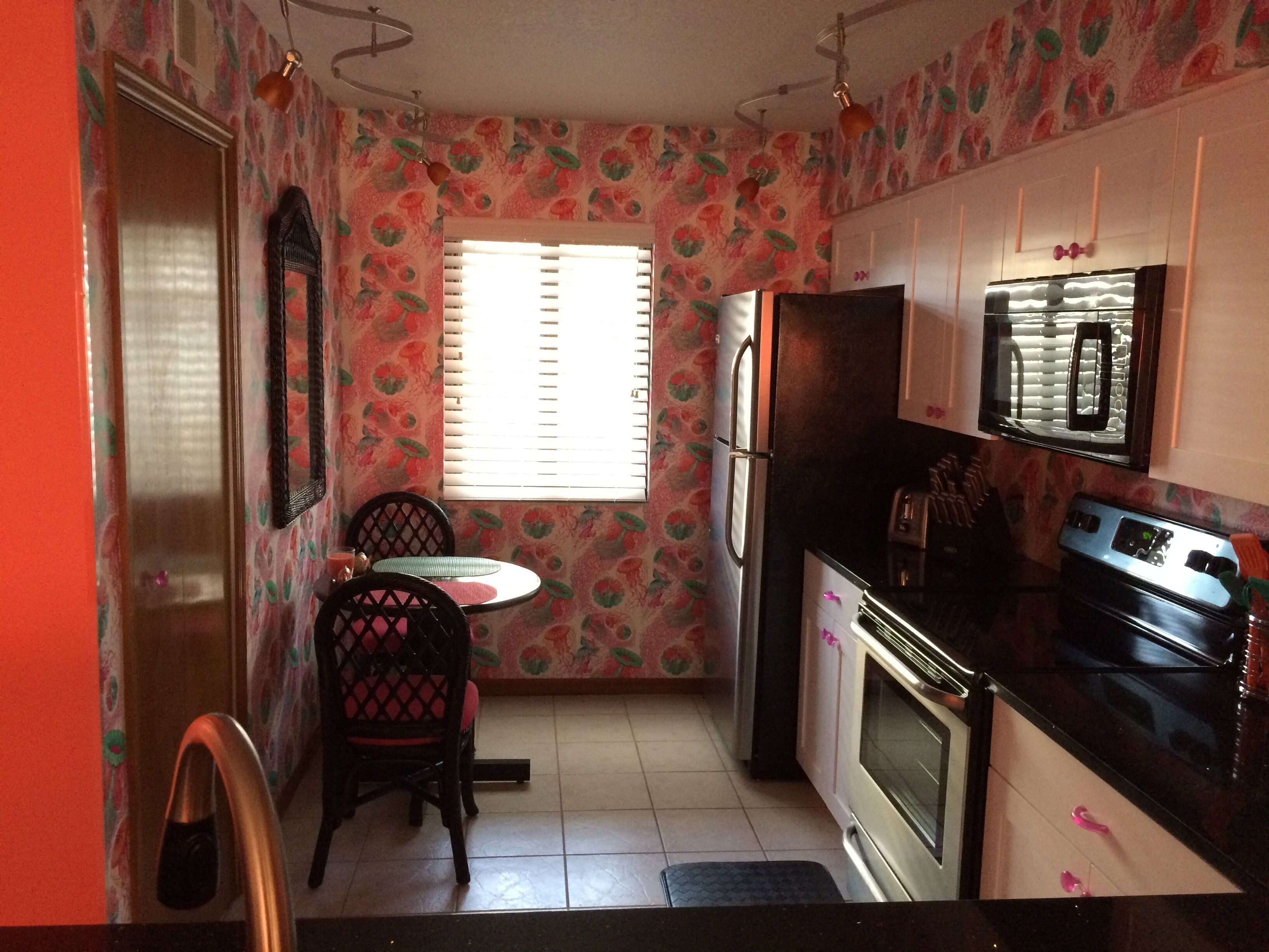 A kitchen with a refrigerator, oven, microwave, and a dining table with chairs.