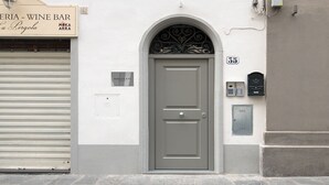 A building with a closed shutter, a door with a decorative arch, and a sign for 'PERGOLA - WINE BAR'. - "MATTONE" - Elegant apartment for 4 people on the 3rd floor. (Firenze)