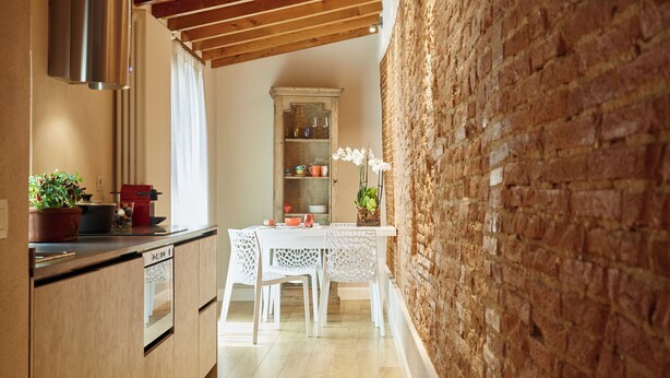 A kitchen with wooden cabinets, a built-in oven, and a brick wall. - "MATTONE" - Elegant apartment for 4 people on the 3rd floor. (Firenze)