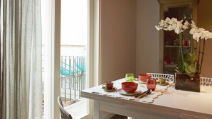 A dining area with a table set for two, a vase of white orchids, and a view of a balcony with blue chairs. - "MATTONE" - Elegant apartment for 4 people on the 3rd floor. (Firenze)