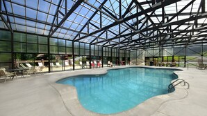An indoor swimming pool with a glass ceiling, surrounded by lounge chairs and tables. - 🏔️Private Sunsets🌅 Sunset Views, Hot Tub & Indoor Pool, near Dollywood (Sevierville)