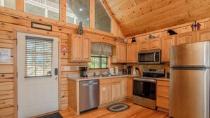 A wooden cabin-style kitchen with a stainless steel refrigerator, microwave, oven, and dishwasher. - 🏔️Private Sunsets🌅 Sunset Views, Hot Tub & Indoor Pool, near Dollywood (Sevierville)